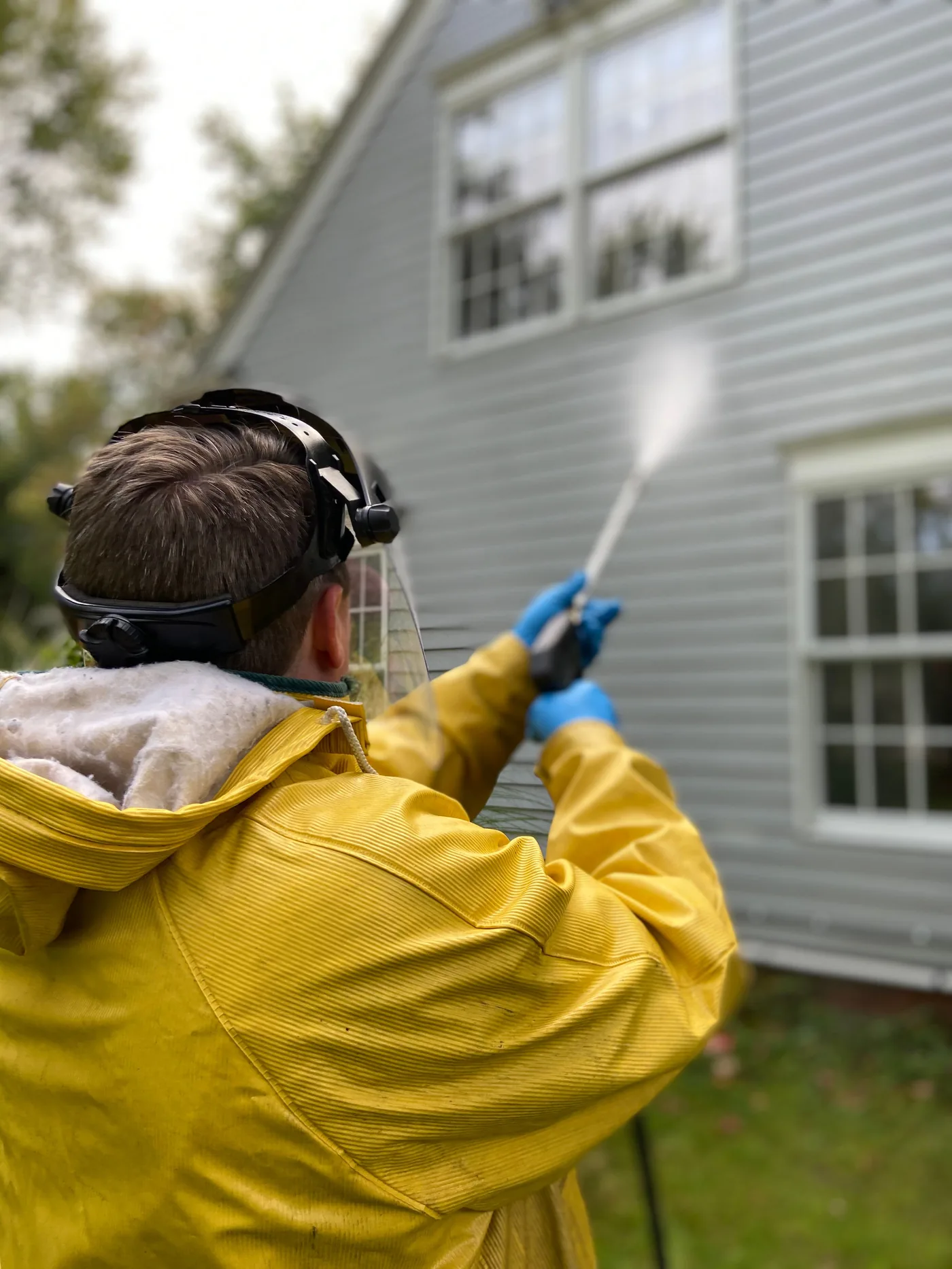 Technician safely pressure washing exterior siding